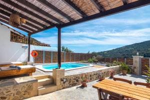 an outdoor patio with a swimming pool and a wooden pergola at Villa Cosmakis in Rodakino