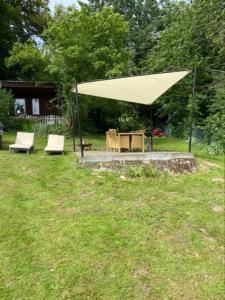 a large yellow umbrella in a yard with two chairs and a table at Hütte für Naturliebhaber - Kinder/ Ponyreiten in Zella-Mehlis