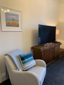 ein Wohnzimmer mit einem Stuhl und einem Flachbild-TV in der Unterkunft Lovely 3 bedroom family friendly cottage in North Berwick in North Berwick