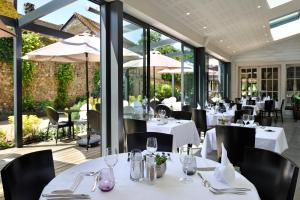 un restaurante con mesas y sillas blancas y ventanas grandes en Le Saint-Jacques, en Cloyes-sur-le-Loir