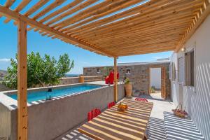 a patio with a wooden pergola and a swimming pool at IL Vento Suites in Mikonos