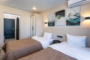 two beds in a room with paintings on the wall at Hotel Irtysh in Ustʼ-Kamenogorsk
