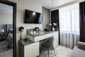 a hotel room with a desk with a television on the wall at Hotel Irtysh in Ustʼ-Kamenogorsk