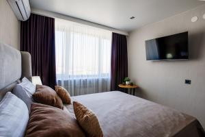 a hotel room with a bed and a flat screen tv at Hotel Irtysh in Ustʼ-Kamenogorsk