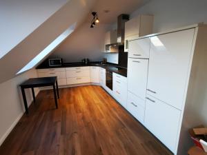 cocina con armarios blancos y mesa negra en Moderne Landhaus-Ferienwohnung mit Balkon en Kempen