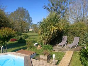 two chairs and a swimming pool in a garden at B&B Le verger in Échillais