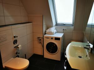 y baño con lavadora y lavamanos. en Moderne Landhaus-Ferienwohnung mit Balkon en Kempen