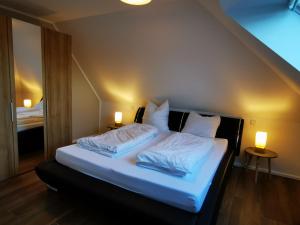 1 dormitorio con 1 cama con sábanas y almohadas blancas en Moderne Landhaus-Ferienwohnung mit Balkon en Kempen