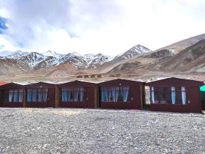 a row of red huts in front of a mountain at Pangong Delight Camps and Cottages in Spangmik