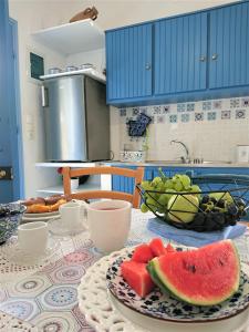 una mesa con un plato de sandía y un tazón de fruta en ~~ Sea Breeze covered house ~~, en Mókhlos