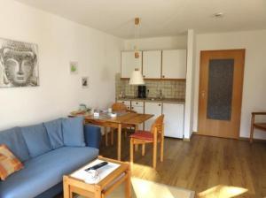 a living room with a blue couch and a kitchen at Bergsonnenblick Bad Hindelang in Bad Hindelang