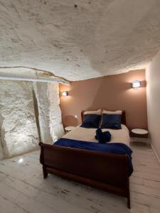1 dormitorio con 1 cama en una pared de piedra en La Trog'Laudy gîte 4 étoiles au coeur des vignes en Vouvray