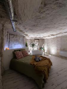 - une chambre avec un lit dans une pièce en pierre dans l'établissement La Trog'Laudy gîte 4 étoiles au coeur des vignes, à Vouvray
