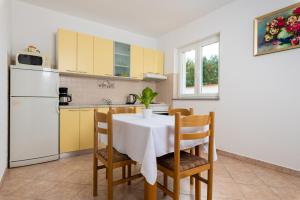 a kitchen with a table and chairs and a white refrigerator at Haus Marija Brovinje in Koromačno