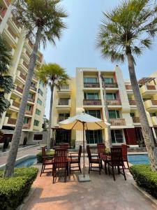 un patio con sillas y una sombrilla frente a un edificio en My Mykonos มายมิโคนอส, en Hua Hin