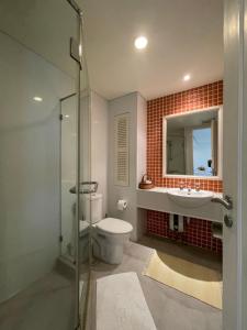 Un baño con inodoro, lavabo y espejo. en My Mykonos มายมิโคนอส, en Hua Hin