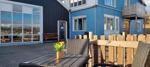 eine Terrasse mit einem Holztisch und Stühlen sowie ein blaues Haus in der Unterkunft Húsavík Cape Hotel in Húsavík
