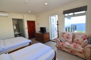 小琉球にあるXinghai Seaview Guesthouseのソファ、ベッド、窓が備わる客室です。