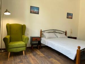 a bedroom with a bed and a green chair at Prista guest rooms in Ruse