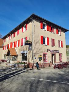 een groot gebouw met rode luiken aan een straat bij Hôtel des Cévennes in Mézilhac