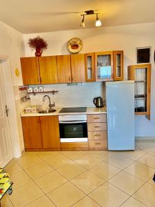 - une cuisine avec des placards en bois et un réfrigérateur blanc dans l'établissement APARTMENT ADRIAN NOVALJA, à Novalja