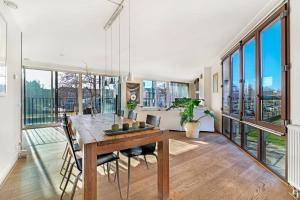 170M2 Appartment with Jacuzzi & Steam bath in center of Amsterdam في أمستردام: غرفة طعام مع طاولة وبعض النوافذ