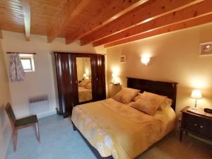 1 dormitorio con cama, silla y espejo en Gîtes de Lohantec, en Mahalon