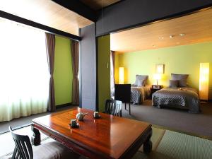 a hotel room with a table and two beds at Ryokan Biyunoyado in Yamanouchi