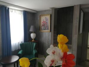 een woonkamer met een groene stoel en bloemen bij Filsdeger Royal Panzió in Eger