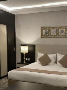 فندق قولد ان في الرياض: غرفة نوم بسرير كبير بها مصباح ومخدات