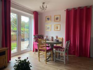 a dining room with red curtains and a table and chairs at The Daytona - Triumph Apartments Meriden NEC 6.5m in Meriden