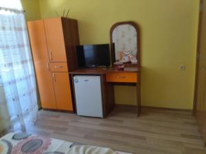 a room with a desk with a television and a refrigerator at Фамилна къща Джоко in Kiten