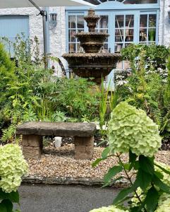 a garden with a stone bench and a fountain at The Stables Townhouse B&B in Birr