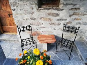 2 Stühle, ein Tisch und Blumen auf der Terrasse in der Unterkunft Cà di Noni in Gordevio
