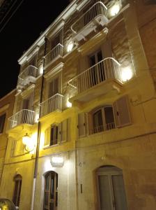 un gran edificio amarillo con balcones blancos y luces en Bed & Breakfast Casa Lopez, en Barletta