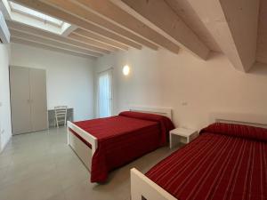 - 2 lits dans une chambre blanche avec des draps rouges dans l'établissement Residence Al Molo - Suite Porta del Mar Sea View - Agenzia Cocal, à Caorle