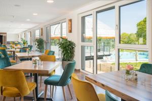 a restaurant with tables and chairs and windows at Thermalhotel Aulendorf in Aulendorf