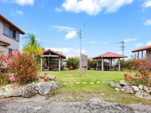 a yard with a park with a bench and buildings at Pension Snadun in Ginoza