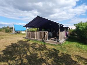 a black tent with a deck in a field at Camping Les Chagnelles in Le Perrier