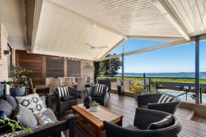 a patio with chairs and tables and a view of the ocean at The Lake House - Luxury home with Pool in Berkeley Vale