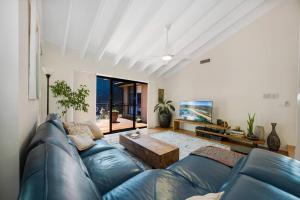 a living room with a blue couch and a table at The Lake House - Luxury home with Pool in Berkeley Vale