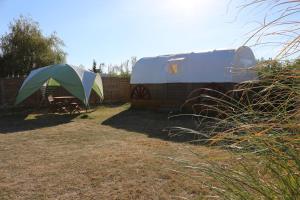 uma tenda e um reboque ao lado de uma cerca em Camping Les Chagnelles em Le Perrier