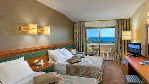 a hotel room with two beds and a television at Özkaymak Incekum Resort - Ultra All Inclusive in Avsallar