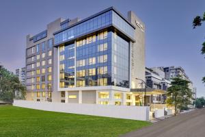 a tall glass building with a lawn in front of it at Park Inn by Radisson Surat in Surat