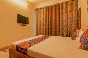 a bedroom with a bed and a tv and a window at FabHotel Yatika Residency in Kolkata