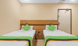 2 camas en una habitación con verde y blanco en Treebo Trend Pride Inn Botanica, en Hyderabad