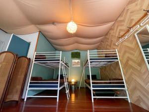 a room with three bunk beds and a ceiling at 秘密基地 NO's ARROW ノーズアロー in Onna