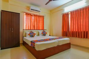 a bedroom with a large bed with red curtains at FabHotel Capital Casa in Kolkata