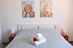 una camera da letto con un letto con asciugamani e due fotografie di Casa Luce Sabaudia a Sabaudia