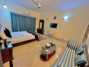 a bedroom with a bed and a couch and a tv at Step Inn Guest House Islamabad in Islamabad